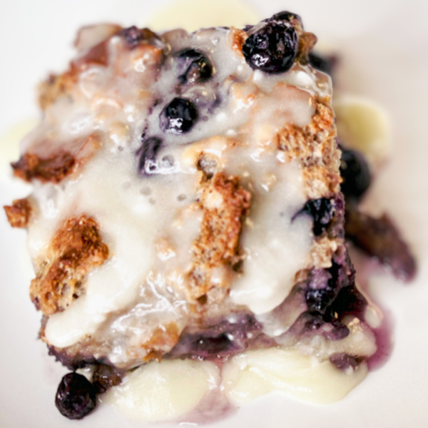 a-piece-of-golden-brown-white-chocolate-and-blueberry-bread-pudding-on-a-pristine-white- plate