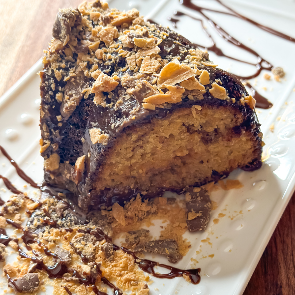 Decadent Butterfinger cake topped with milk chocolate and adorned with crushed butterfinger pieces